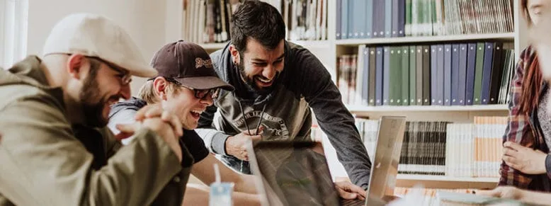 Three Students look and laugh at a laptop